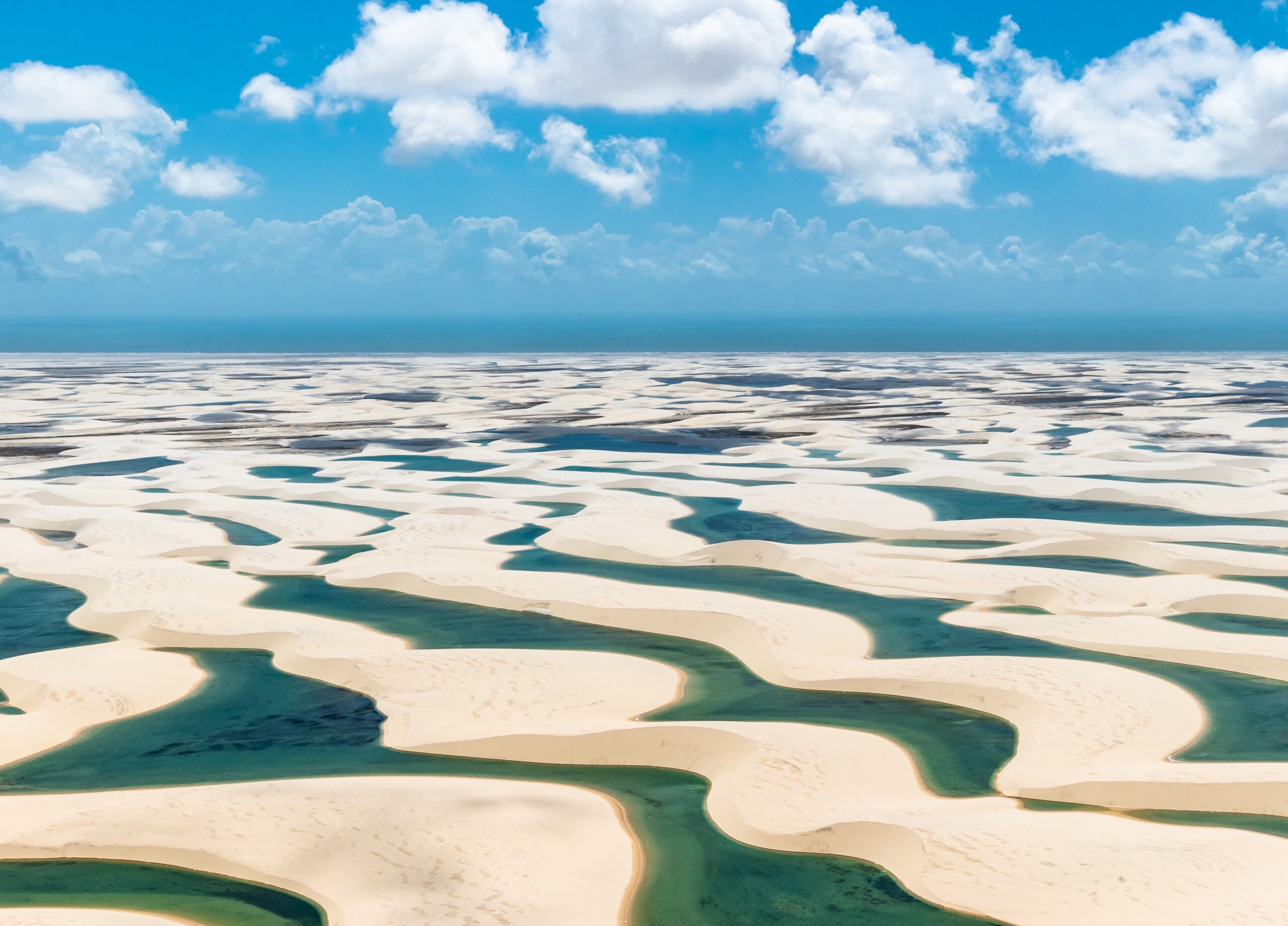 Fresh water collecting in the valleys between sand dunes in the Lençóis Maranhenses National Park in Brazil. A layer of rock beneath the sand prevents the rain water from dissipating during the rainy season, resulting in a broad expanse of lagoons.