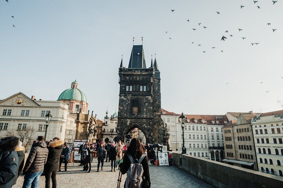 Tourists walking on Charles Bridge in Prague with iconic Old Town Bridge Tower.