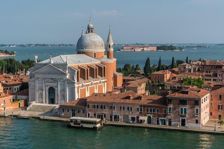 A beautiful view of a Venetian church and canal under a clear blue sky, ideal for tourism and travel themes.