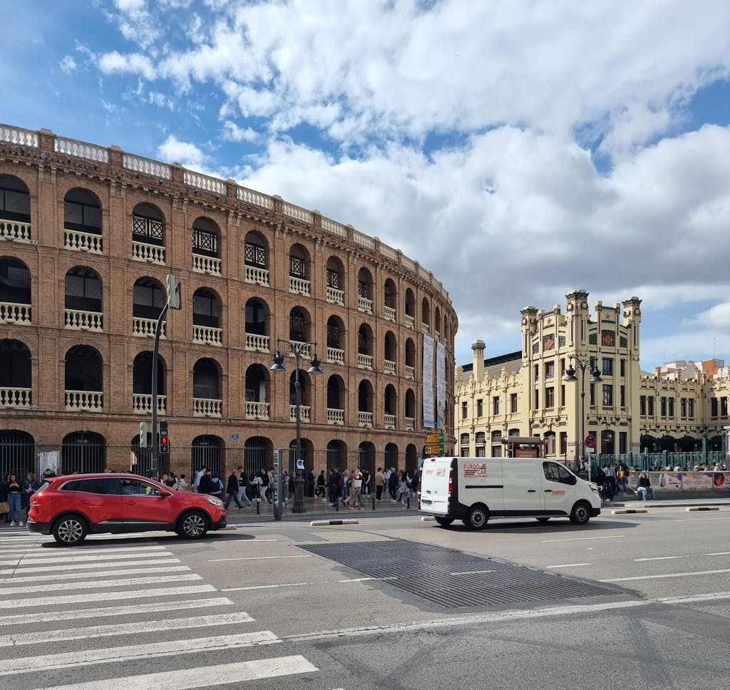 View of Valencia's iconic bullring and surrounding architecture under a partly cloudy sky.